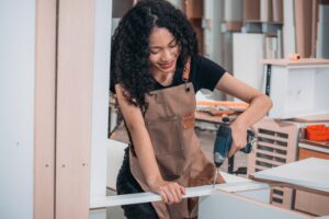 Experienced carpenter expertly drills precise holes, crafting furniture with practiced skill