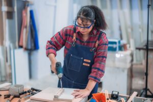 Experienced carpenter expertly drills precise holes, crafting furniture with practiced skill